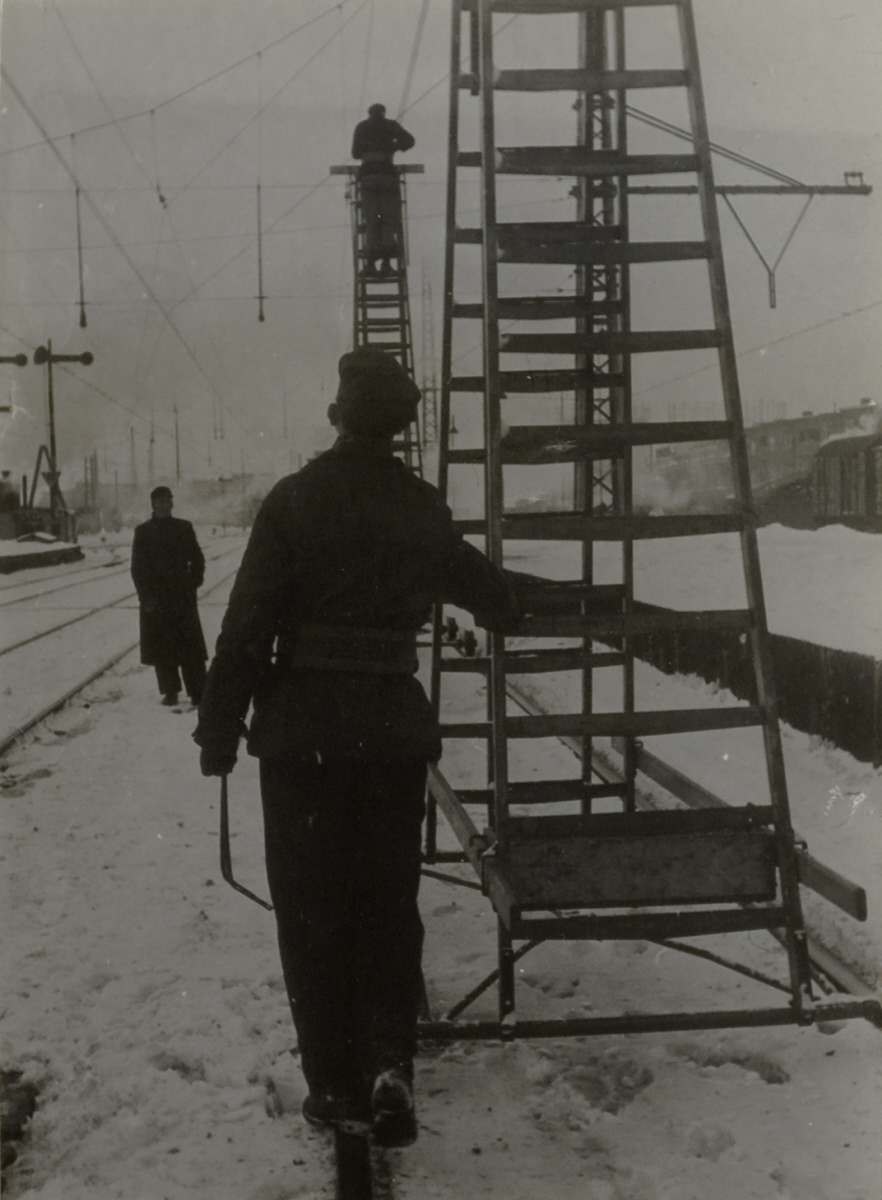 Een werkman duwt een ladder door de sneeuw