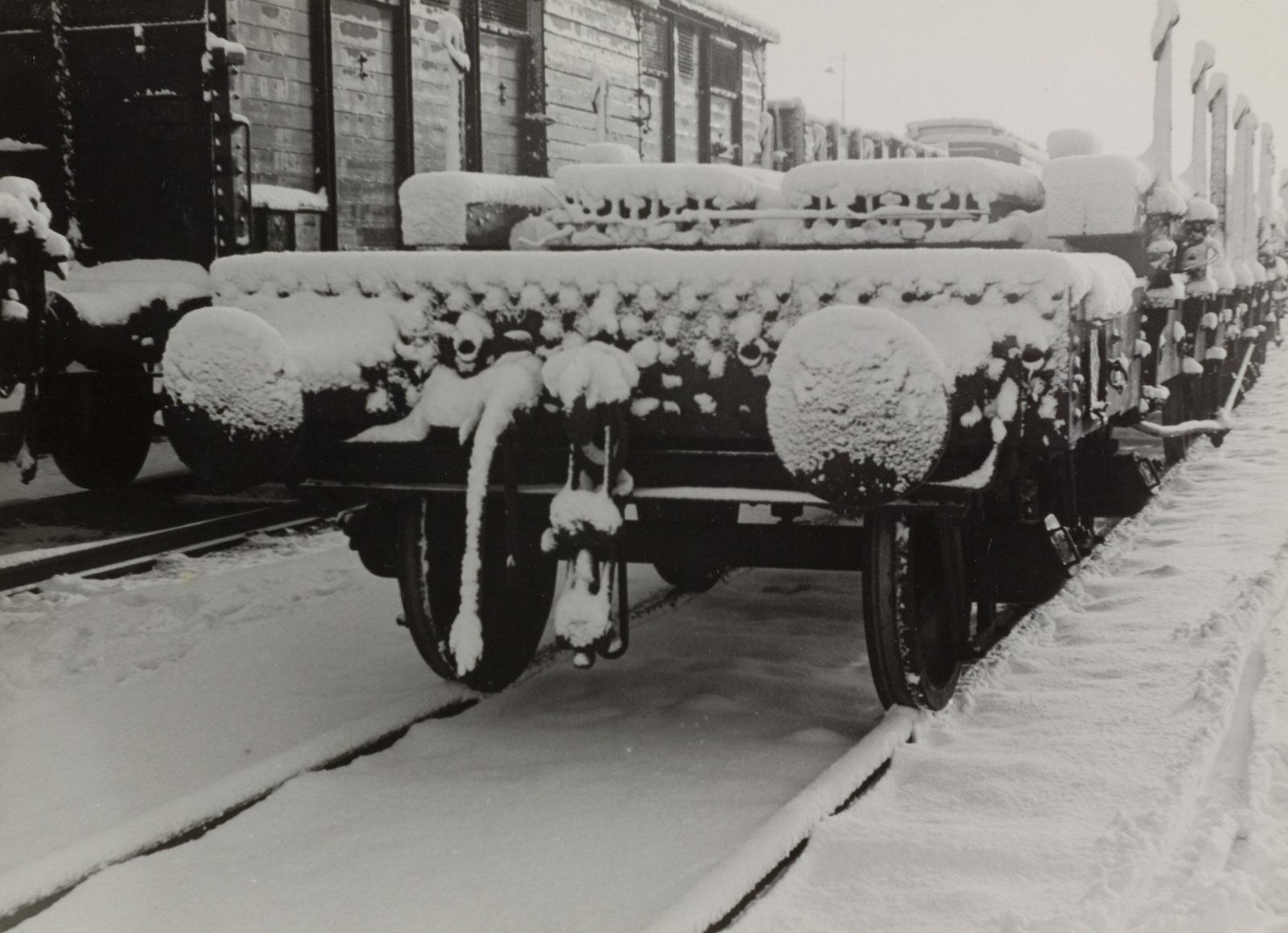 Emplacement met platte wagens geladen met rails in de sneeuw