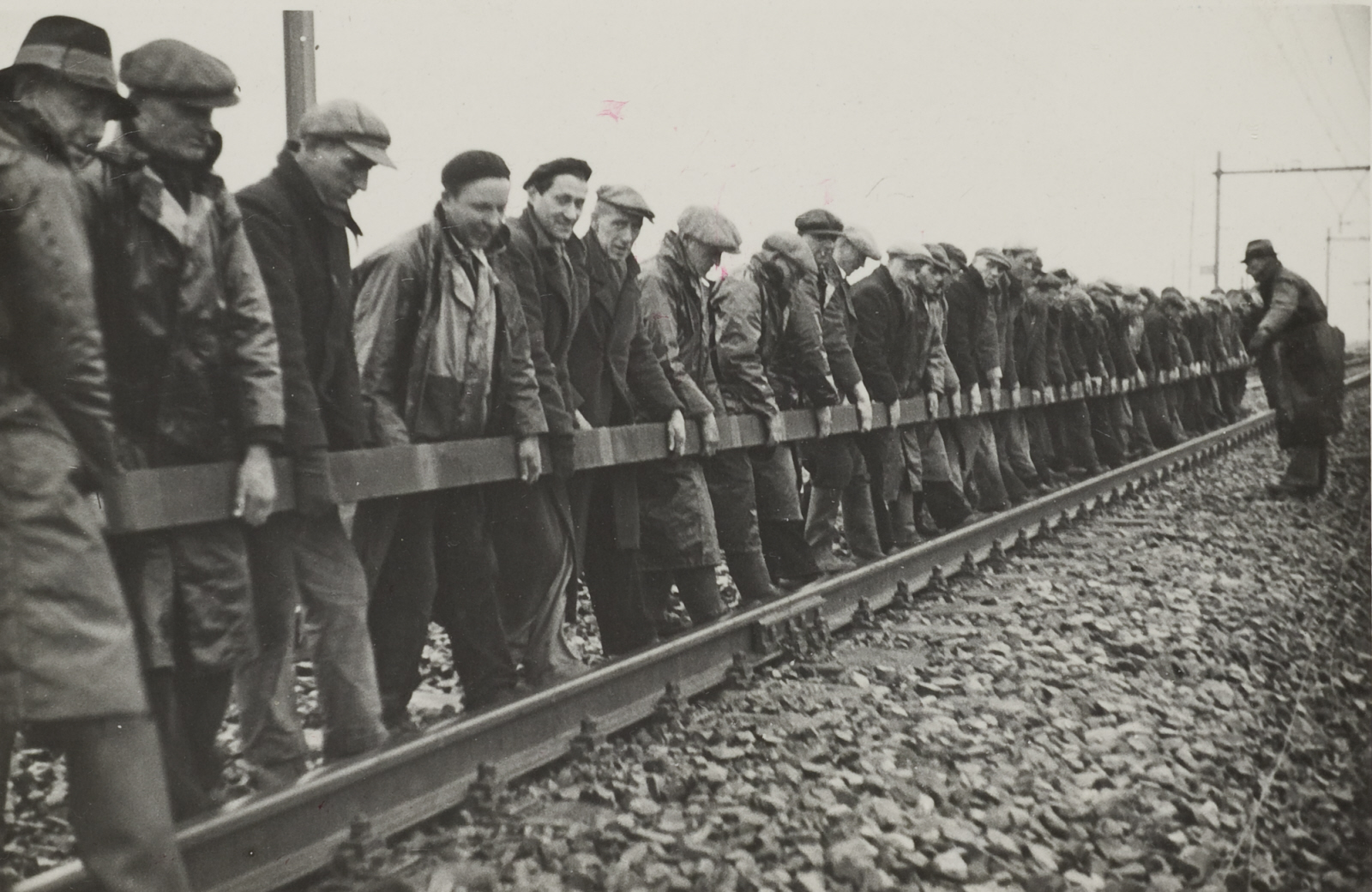 Werkmannen houden een spoorstaaf vast baanvak Utrecht - Arnhem