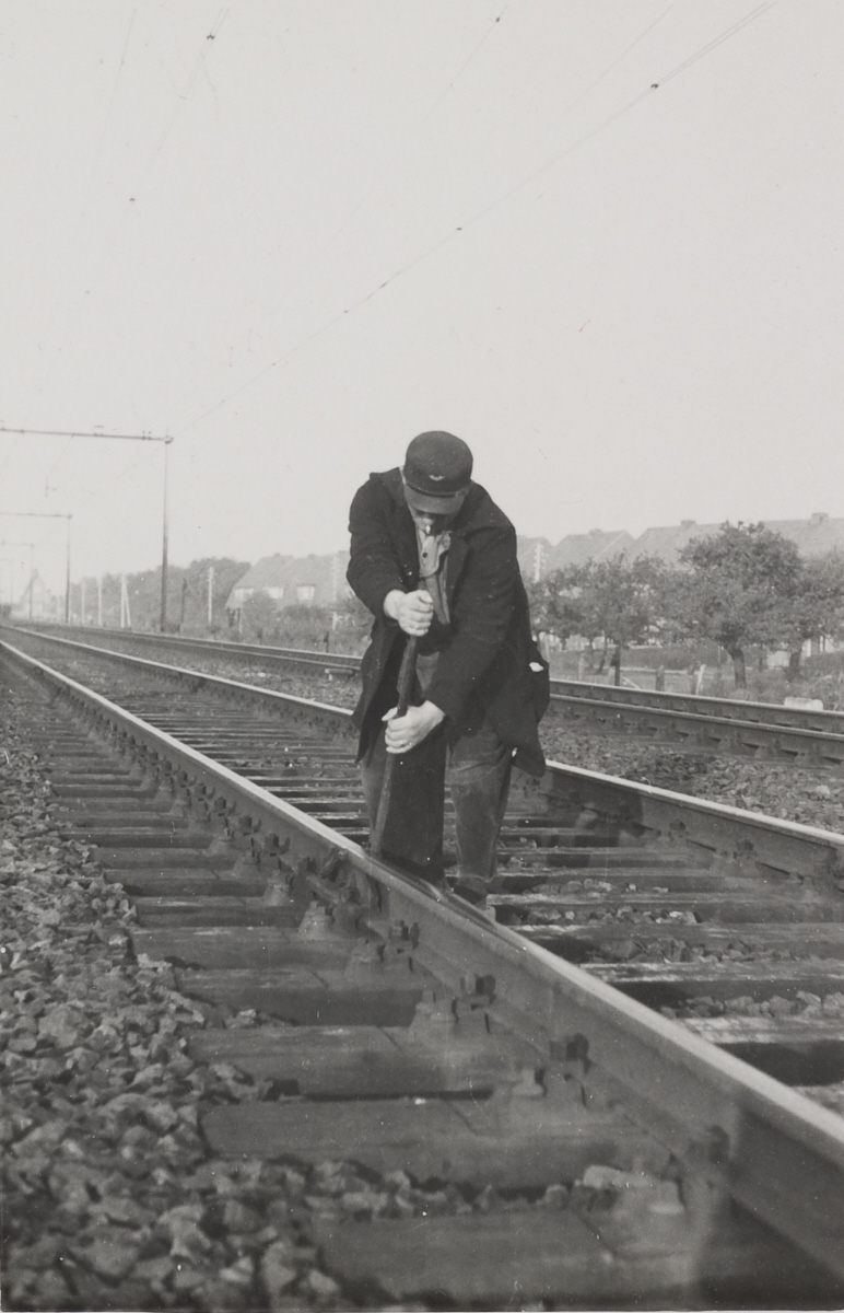 Baanwerker houdt een staaf vast op het spoor tussen Arnhem en Utrecht