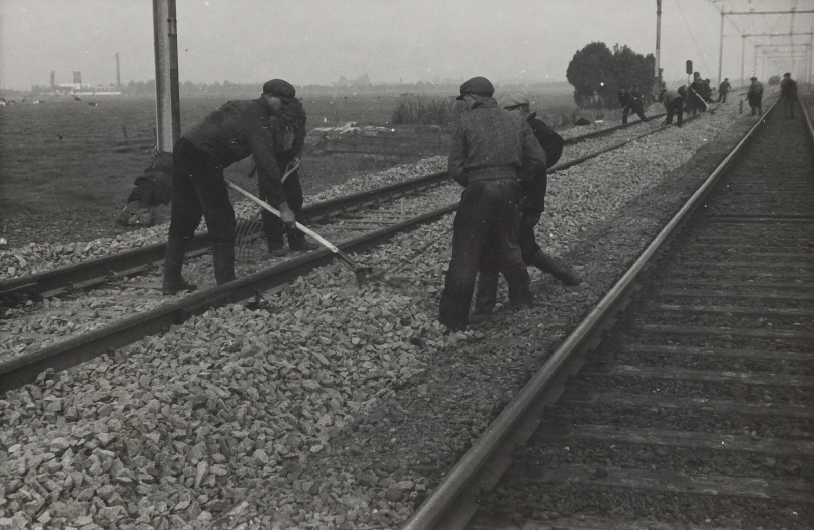 Werkmannen verdelen ballastmateriaal op het spoor bij Abcoude