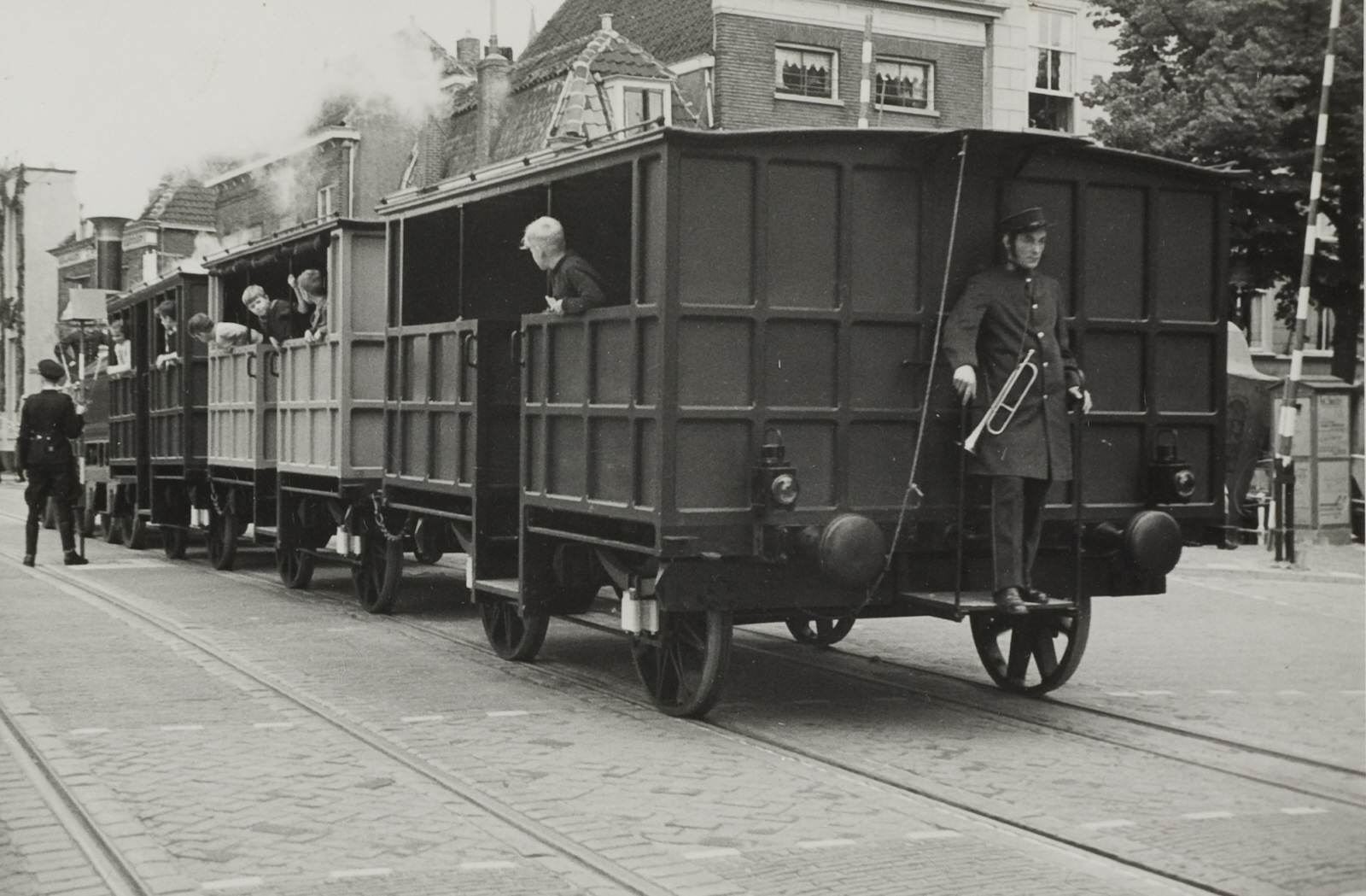 Stoomlocomotief 'De Arend' met wagons in de straten van Delft met een conducteur achterop