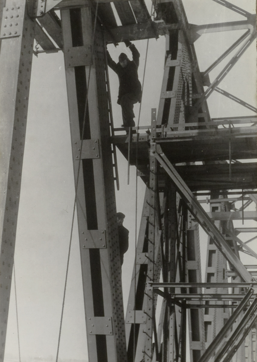 Een werkman aan het werk in de overspanning van een brug