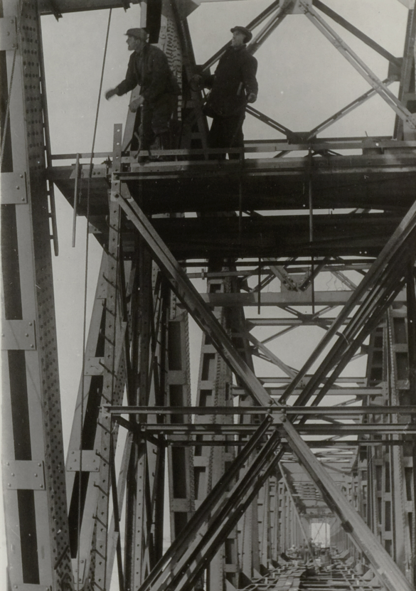 Twee werkmannen aan het werk in de overspanning van een brug