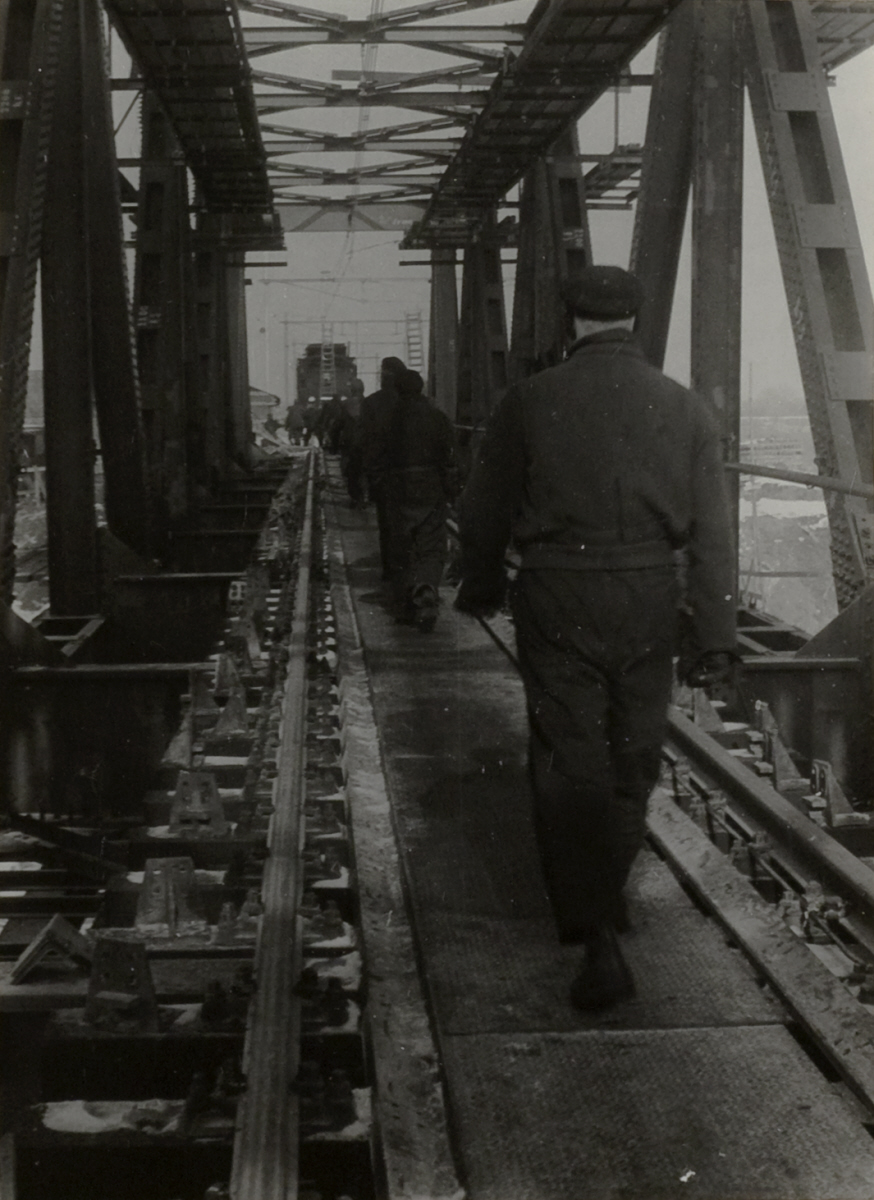 Werkmannen lopen over het spoor op een brug